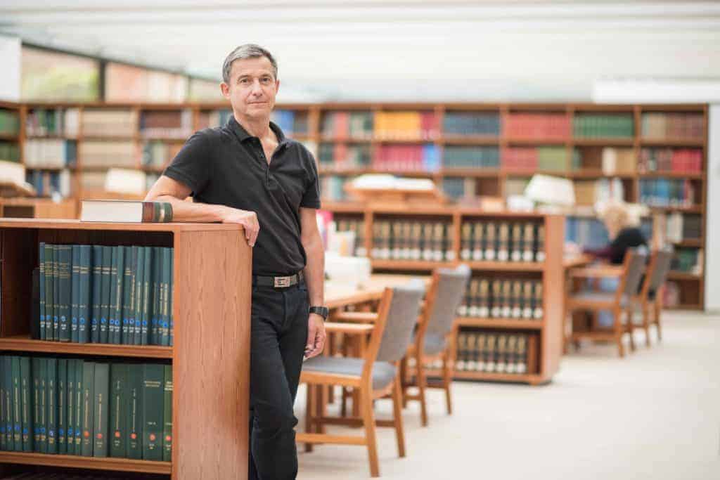 Didier Fassin in front of a library