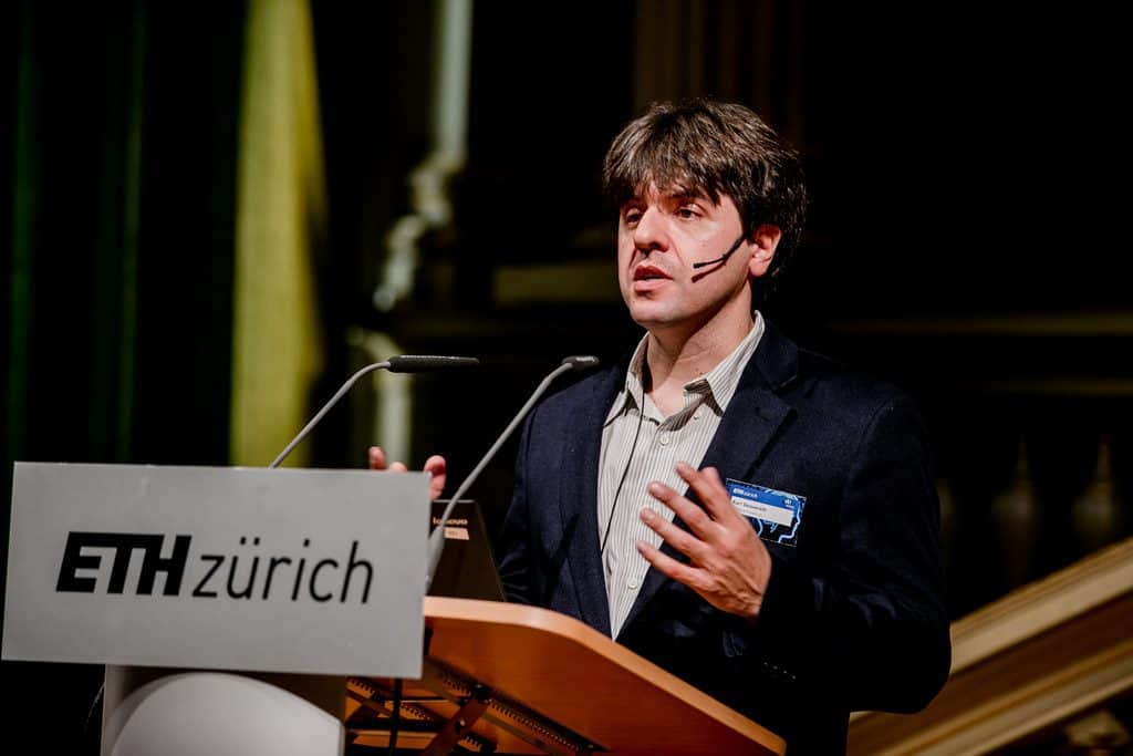 Karl Deisseroth speaks into a microphone in front of people