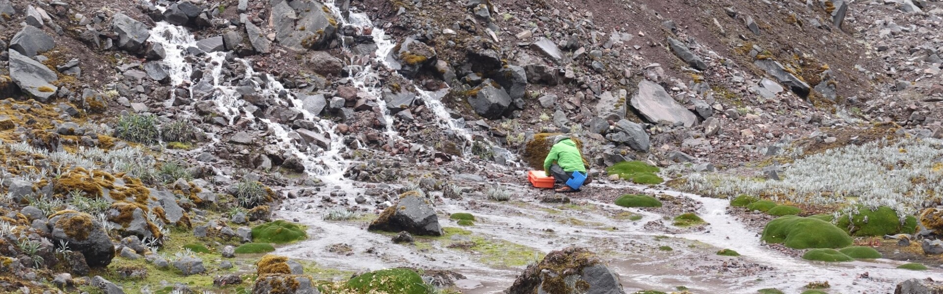 Man bowing down at a rock at the edge of a mountain